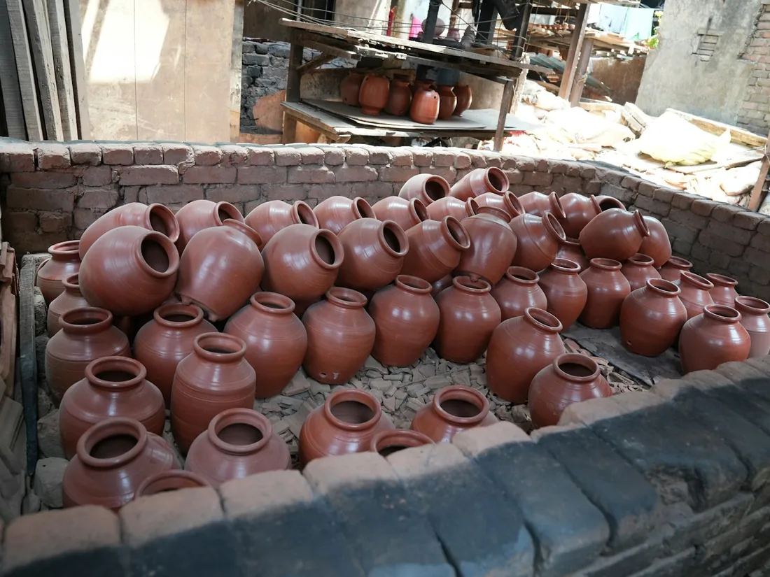 Piezas de barro sin esmaltar apiladas dentro de una cámara de ladrillo antes de la cocción.